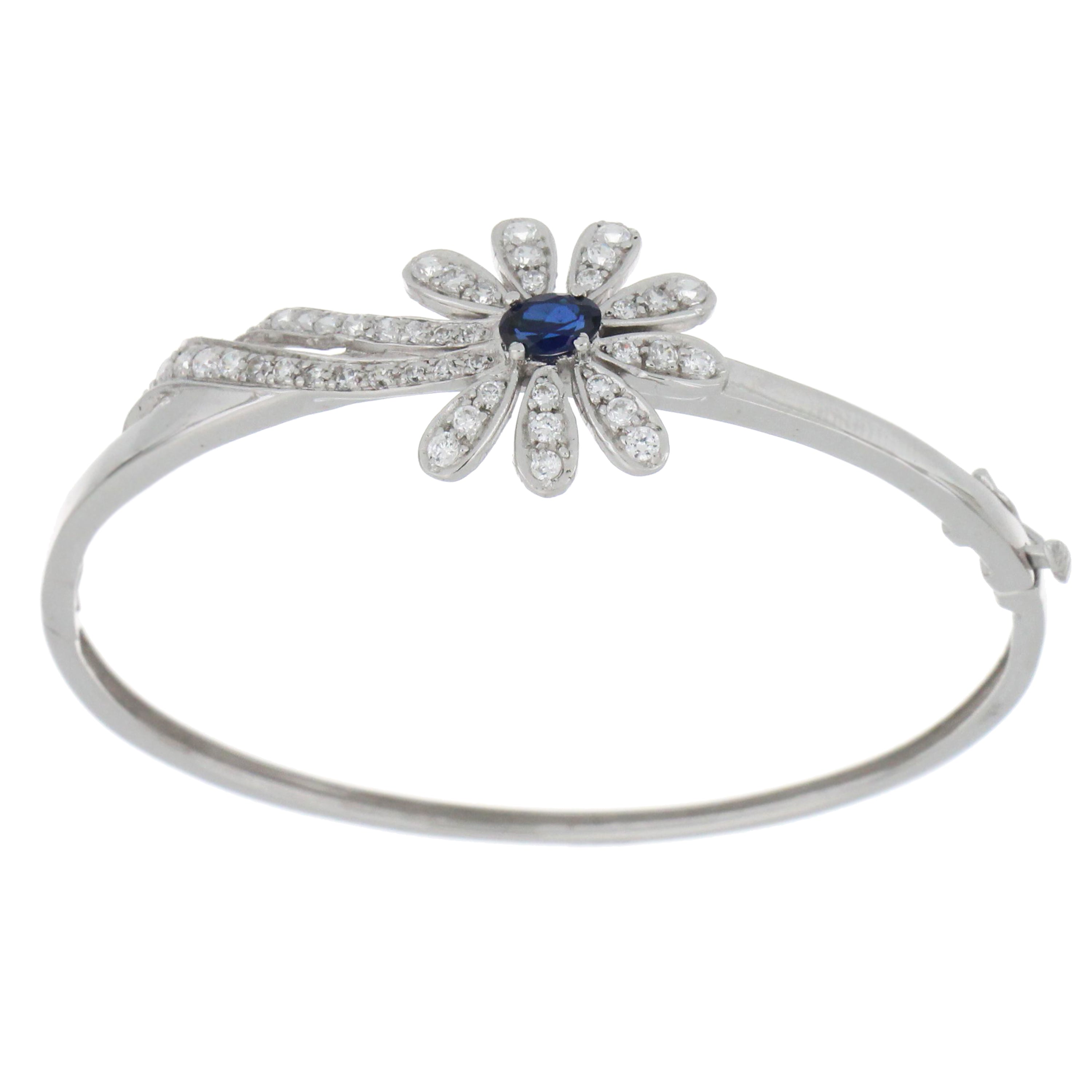 18kt white gold flower style bangle featuring central oval synthetic blue sapphire surrounded by cubic zirconia, top angle view