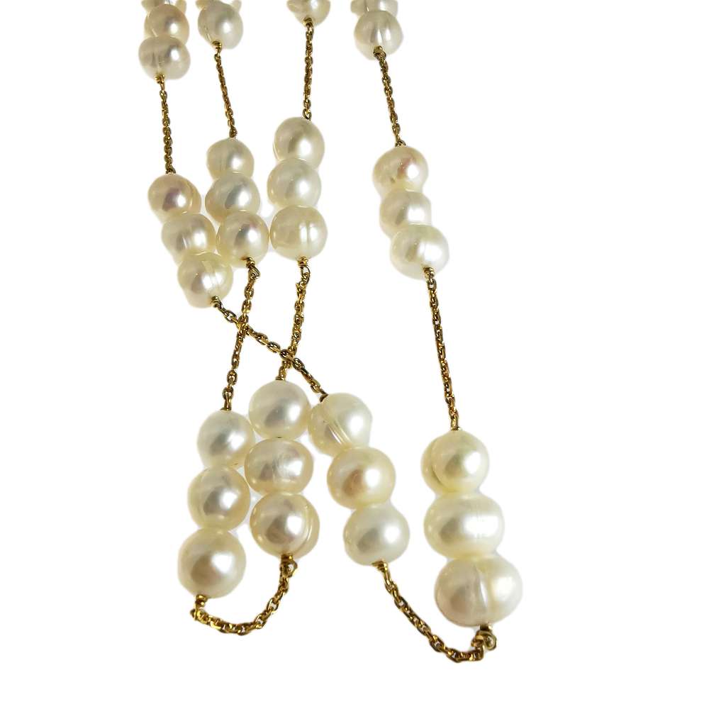 Close-up of white pearls on gold cable-link chain