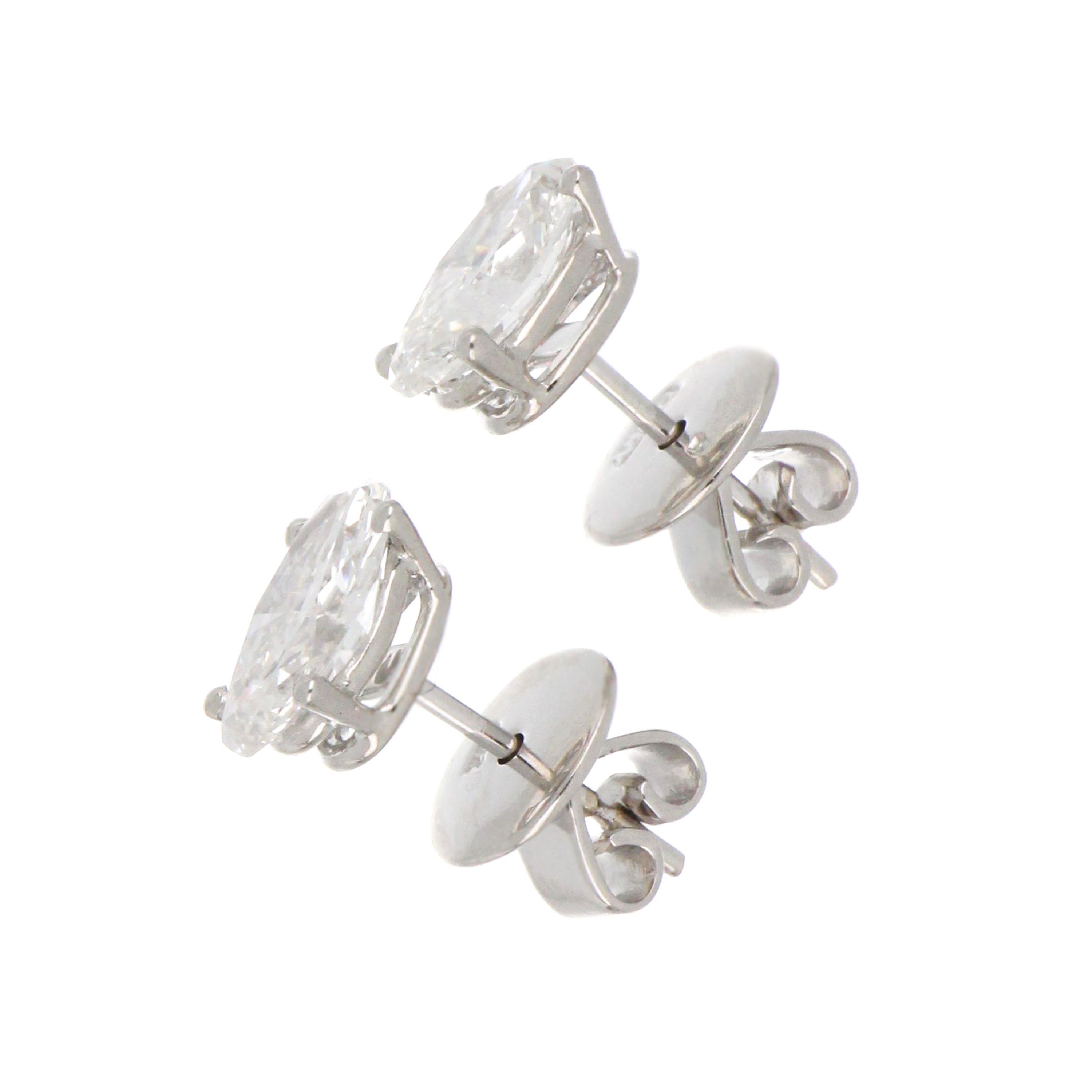 Pair of 18kt white gold diamond stud earrings displayed on black background emphasizing oval shape and premium quality