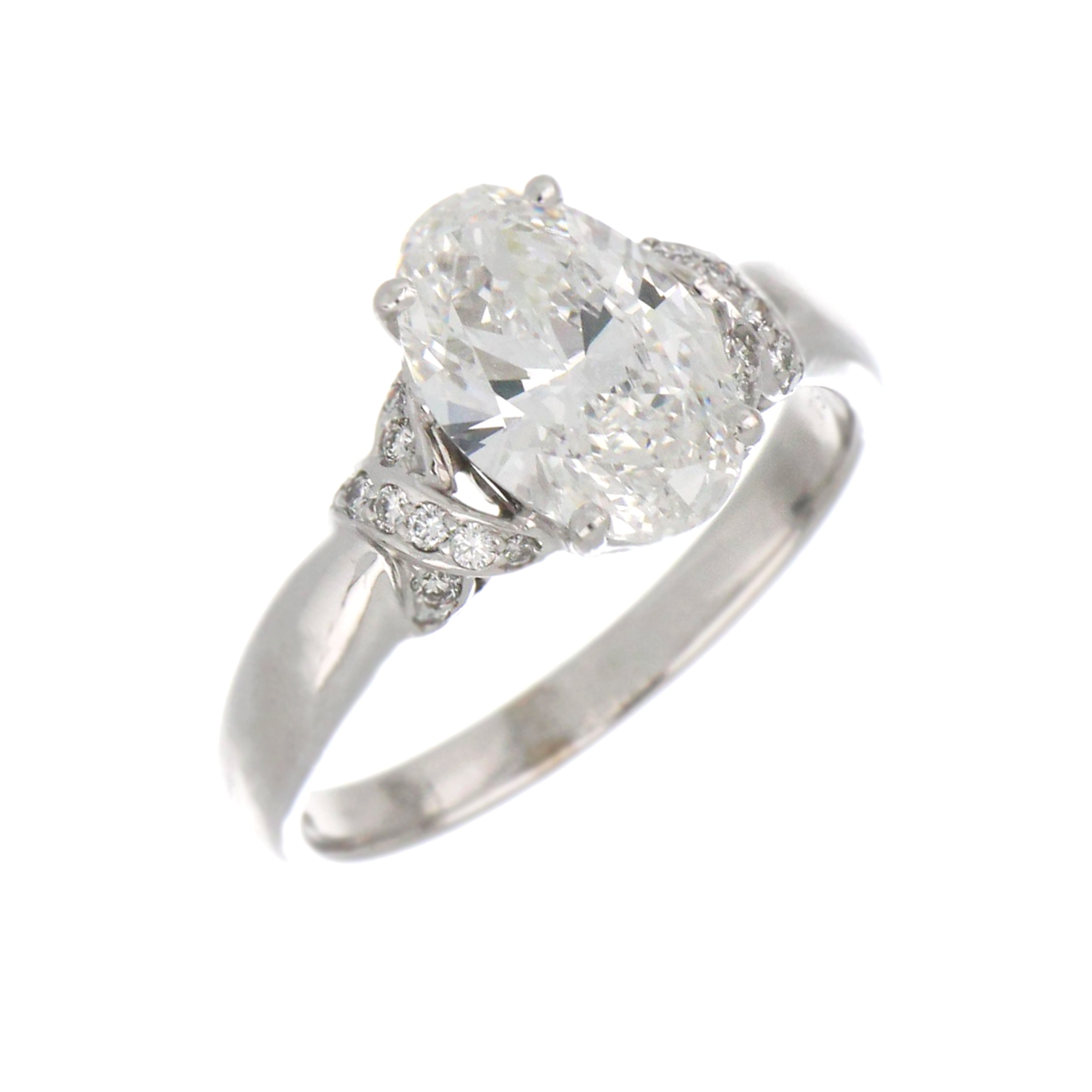 Close-up of claw setting holding oval diamond surrounded by smaller round diamonds on white gold band