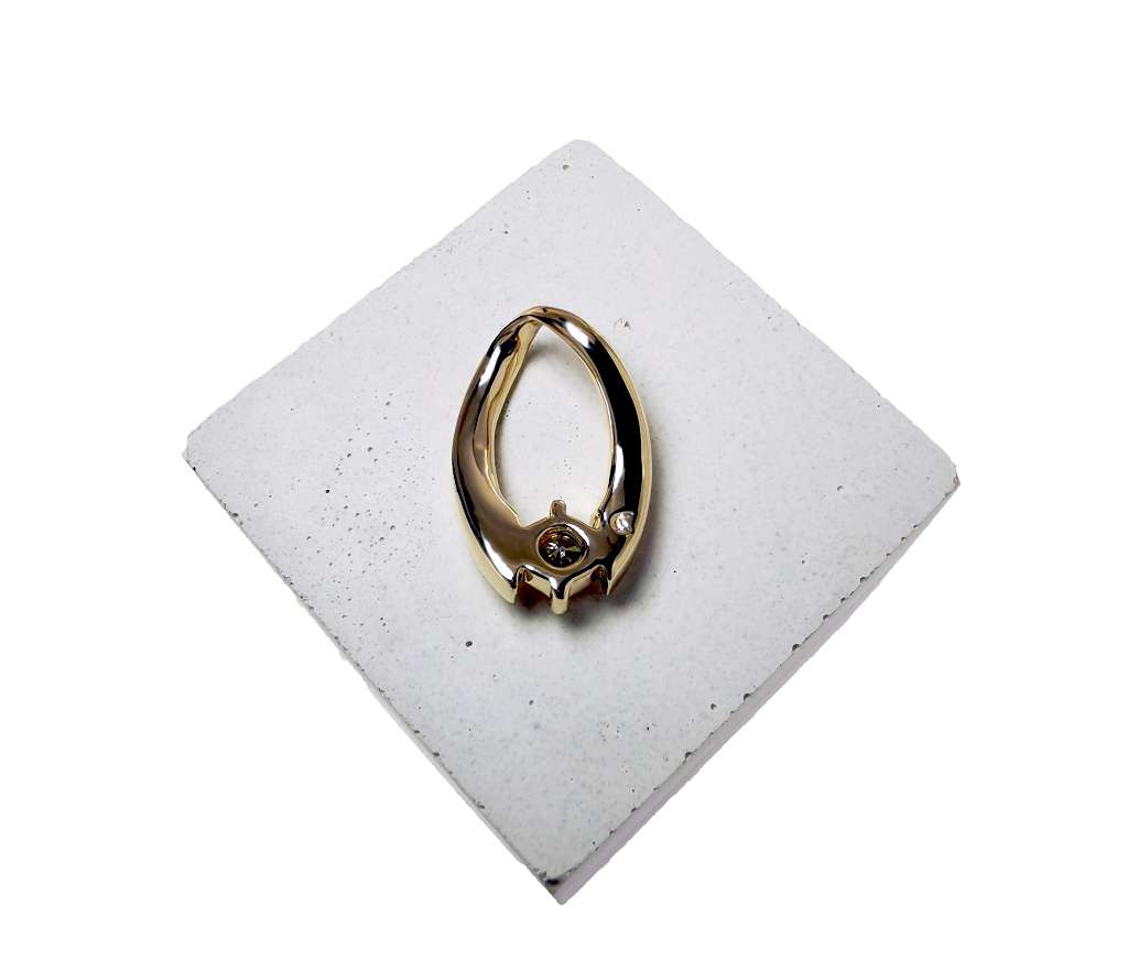 angled view of sculptural gold pendant featuring single round diamond