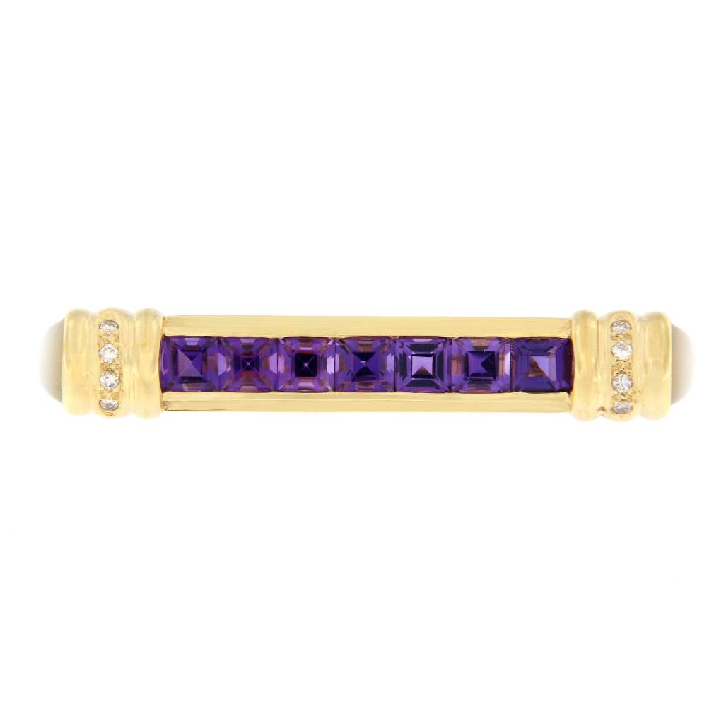 Close-up of 18K yellow gold brooch showcasing purple square step cut amethysts, round cabochon moonstones, and sparkling diamonds from top view