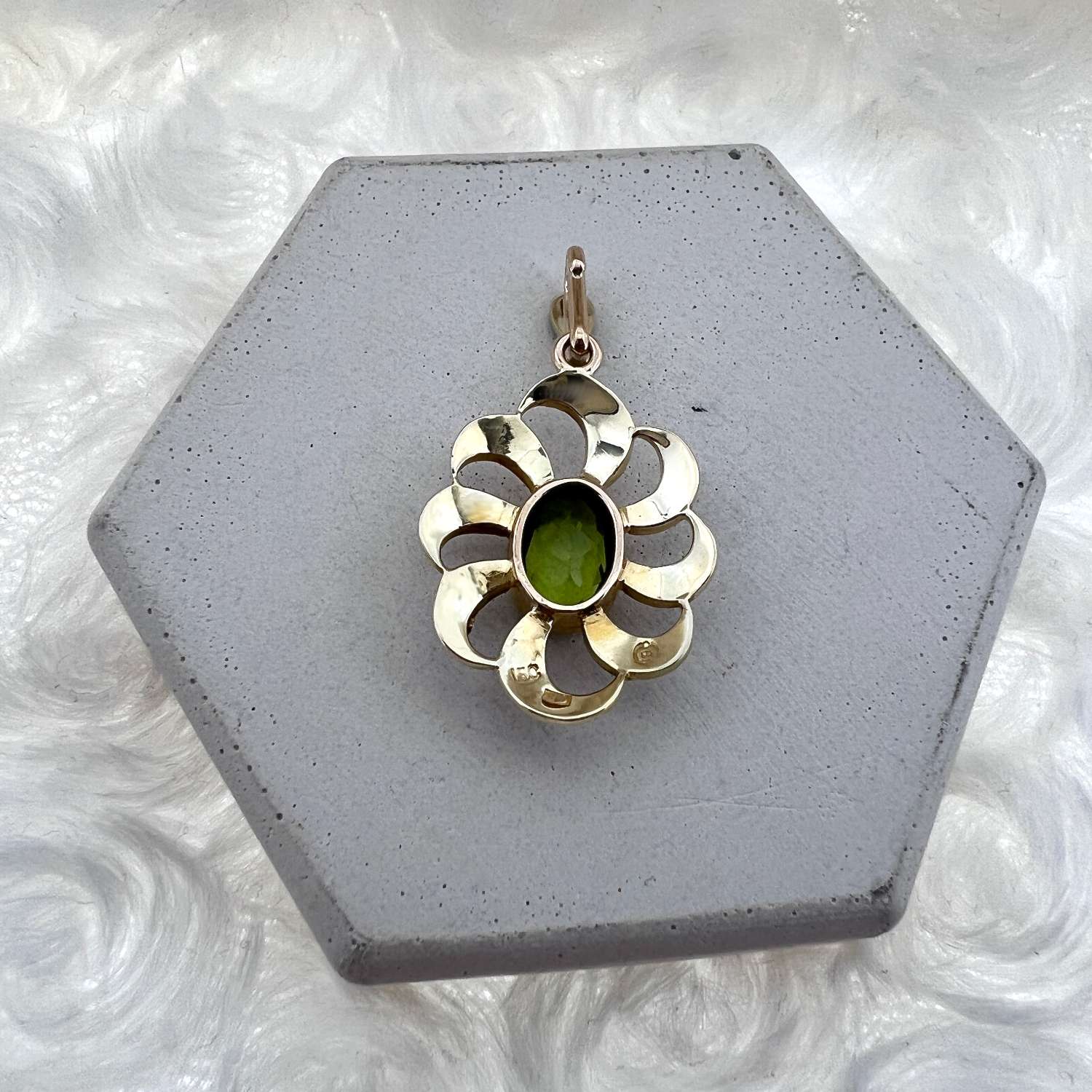 Close-up of 15kt yellow gold pendant showing green oval peridot and pearl halo, side angle
