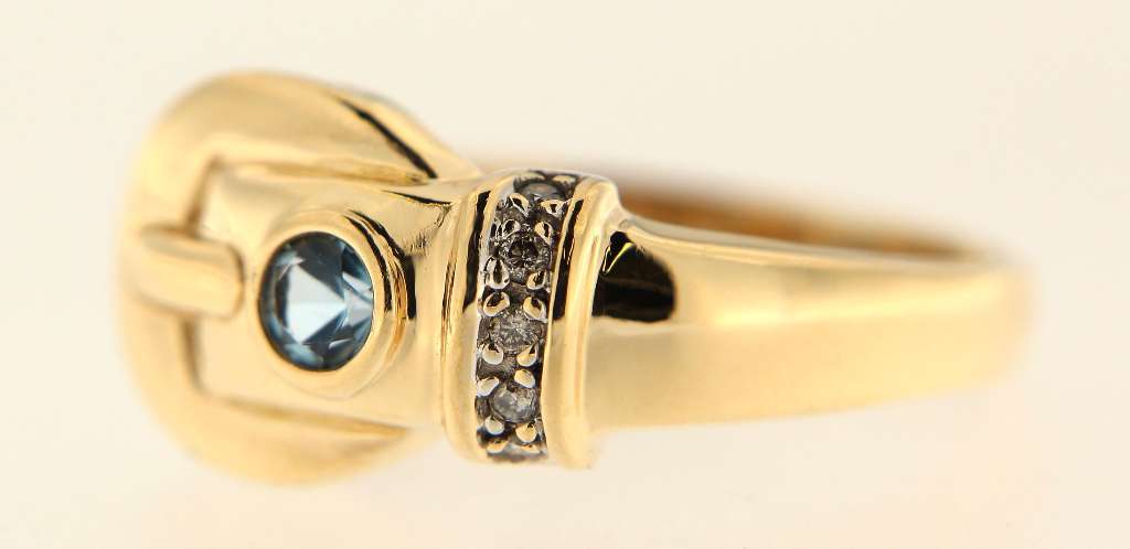 Close-up detail of 14kt yellow gold ring shank and gemstone settings featuring round blue topaz and full cut diamonds