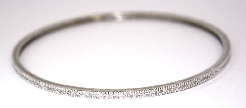 Detailed view of round brilliant cut diamonds on 14kt white gold bangle, showing clarity and sparkle