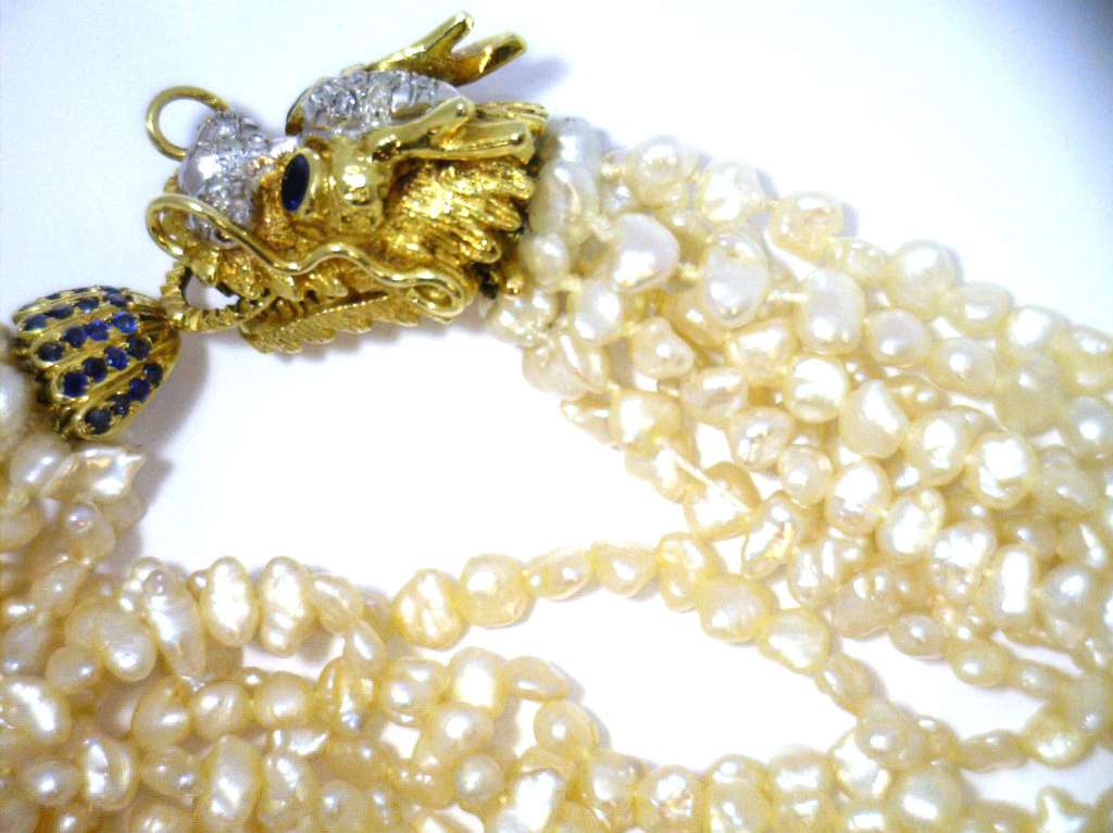 Side angle of eight strand freshwater pearl necklace showcasing lustrous pearls and intricate gold clasp detailing