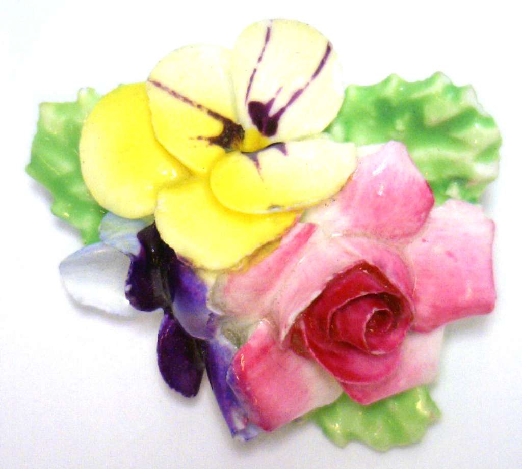 Hand-painted porcelain floral bouquet brooch, close-up of delicate painted flowers on smooth white porcelain surface