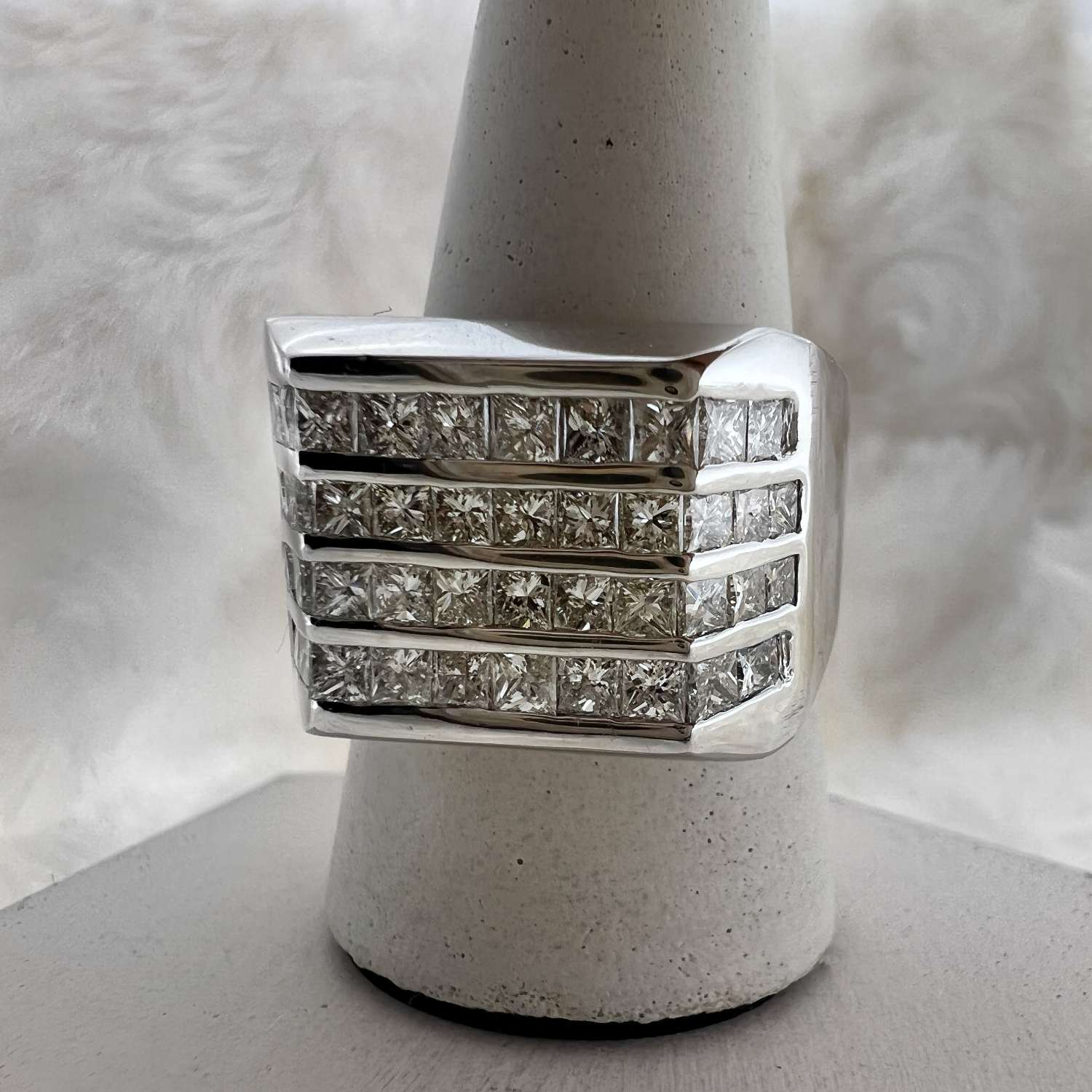 Side angle of 18kt white gold engagement band showcasing detailed channel setting with sparkling princess cut diamonds.