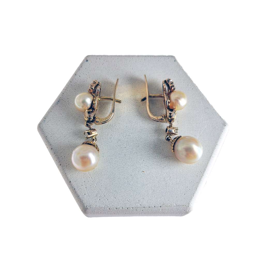 Antique 9kt yellow gold dangling earring featuring rose cut diamonds and two cultured pearls, front angle.
