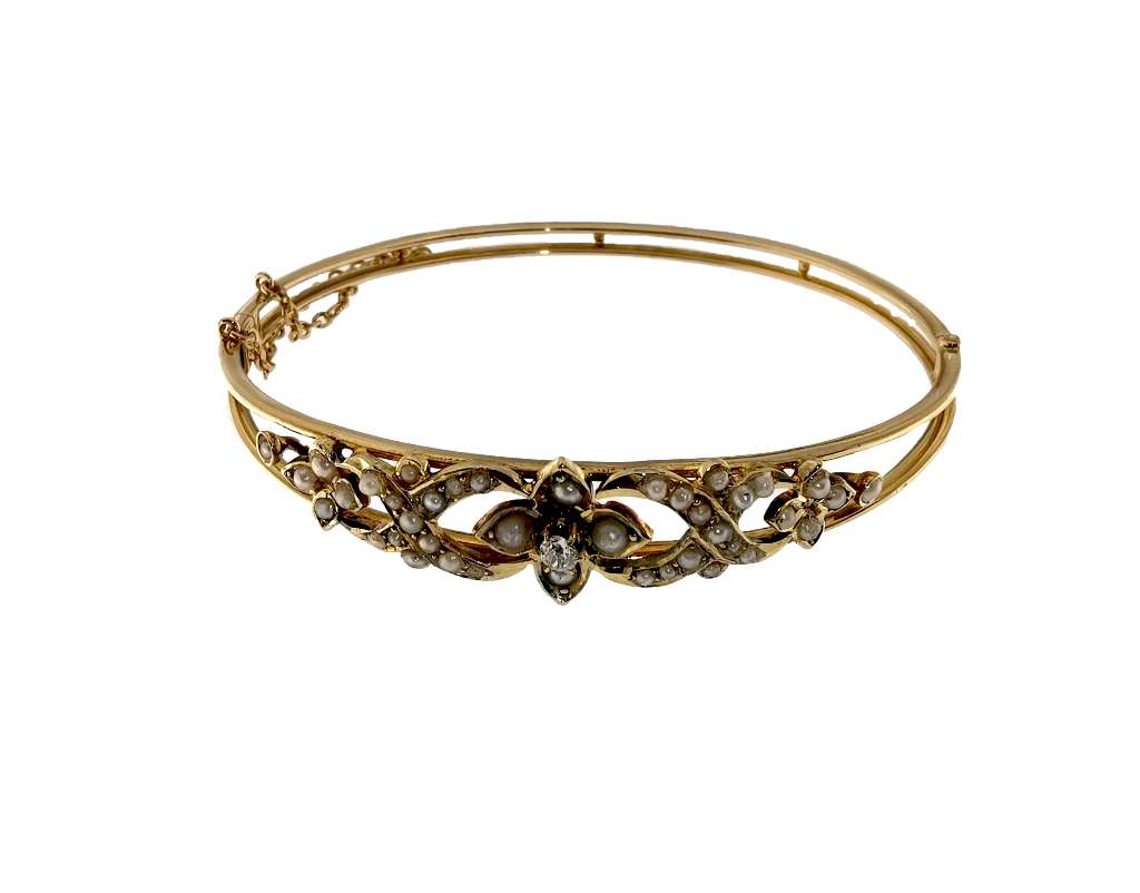 Side angle of antique 14kt yellow gold bangle showcasing round diamond and seed pearl motif