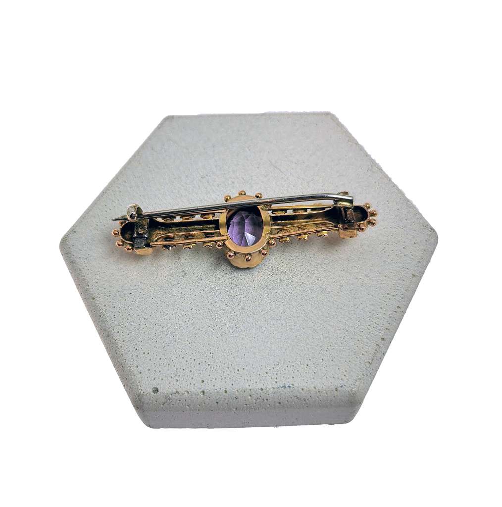 Side view of antique 9kt yellow gold amethyst brooch with seed pearl detailing highlighting vintage design