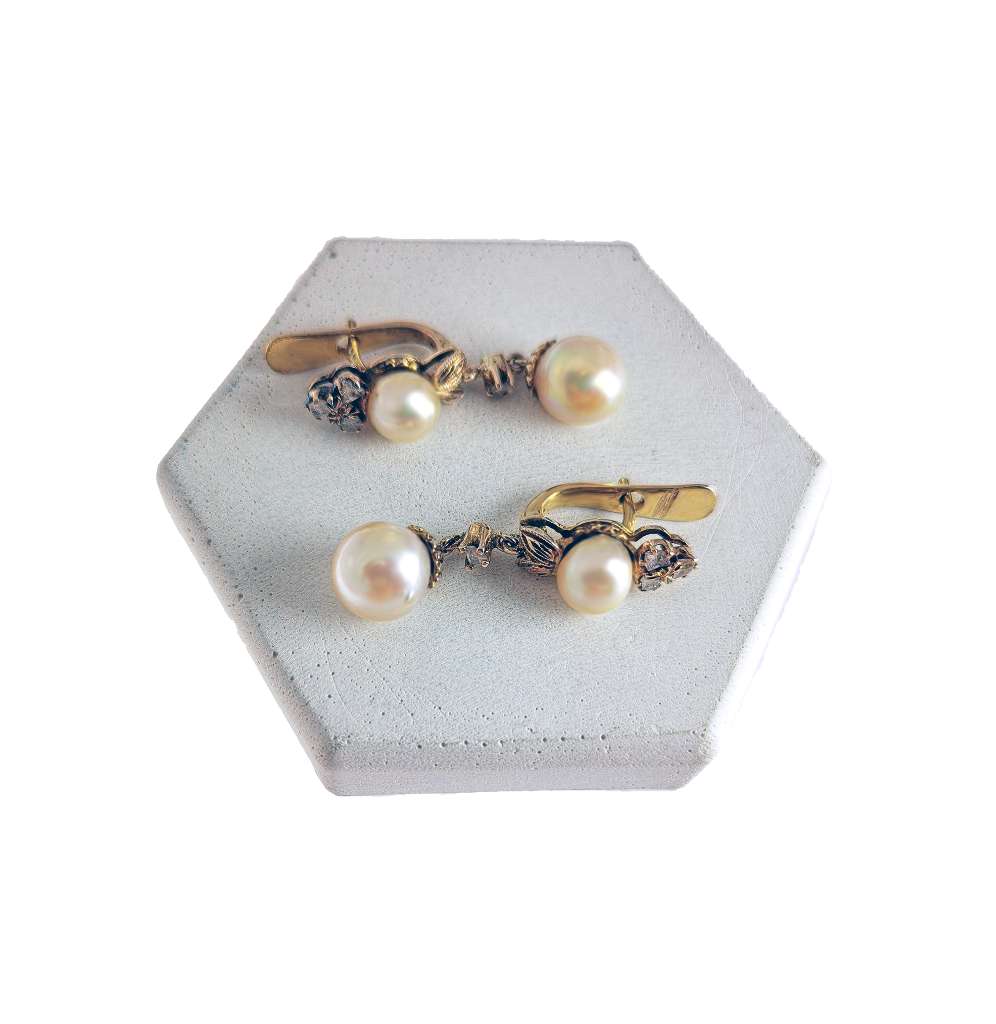 Close-up of antique 9kt yellow gold earring showcasing white cultured pearls and rose cut diamonds, side view.
