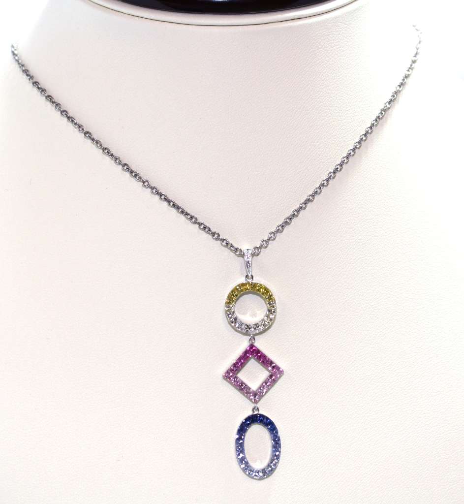 Close-up of multicolor sapphires set in 18kt white gold pendant highlighting vibrant yellow, pink, blue, and white gemstones, detailed craftsmanship visible