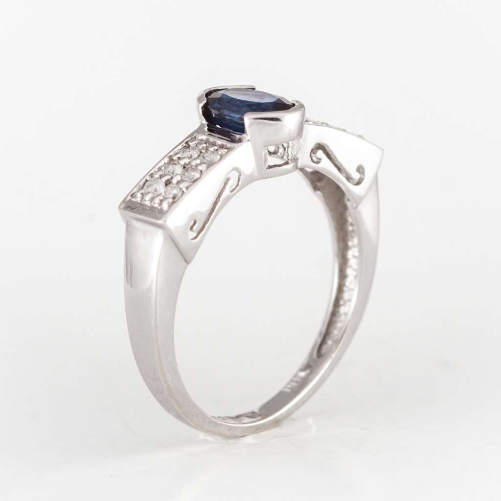 Close-up of bezel set oval blue sapphire and twelve round cut diamonds on white gold band