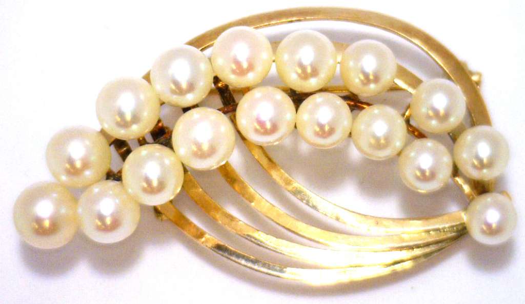 Close-up of 14kt yellow gold brooch pendant featuring 17 white pearls arranged elegantly, showcasing lustrous pearl surface and gold setting
