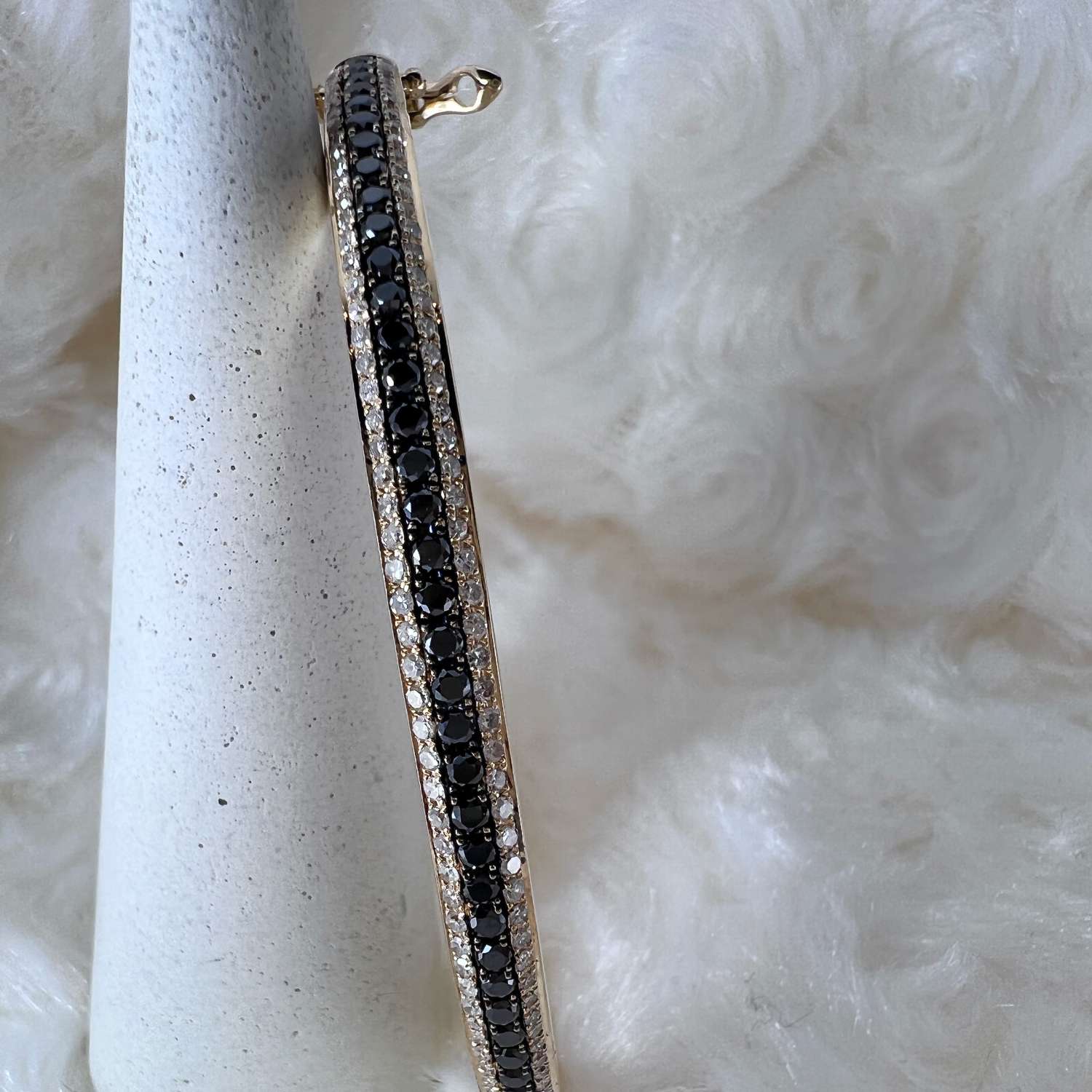 Side profile of 14kt yellow gold diamond bangle with black and colorless round diamonds, highlighting total weight elegance