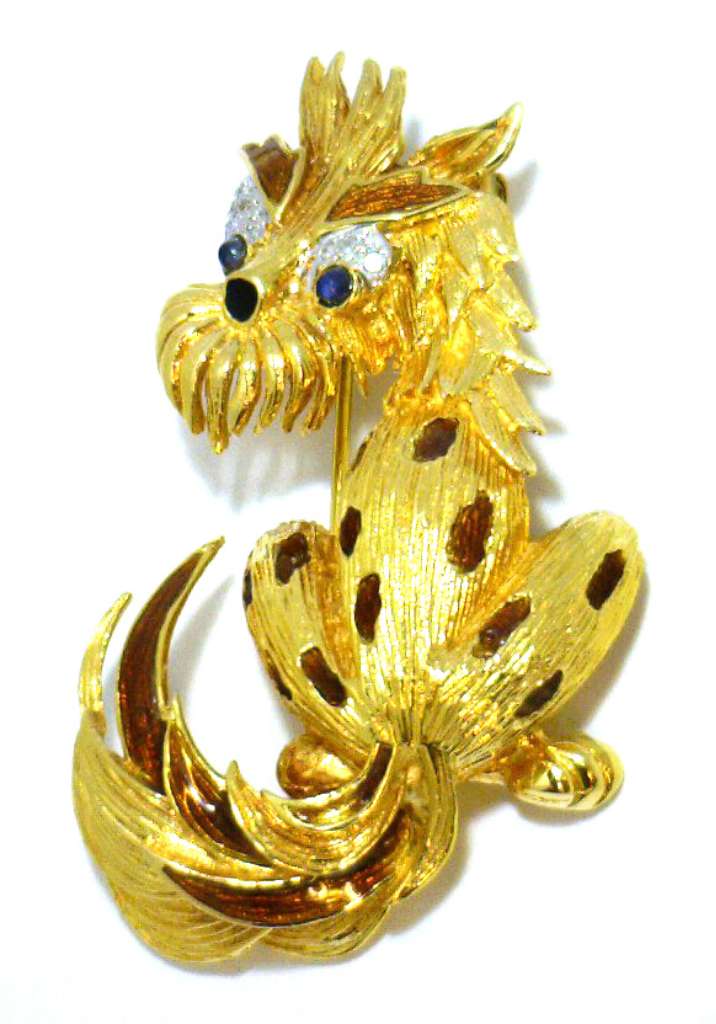 Close-up angle of 18kt yellow gold dog brooch displaying round blue cabochon sapphires and single cut diamonds with enamel detailing