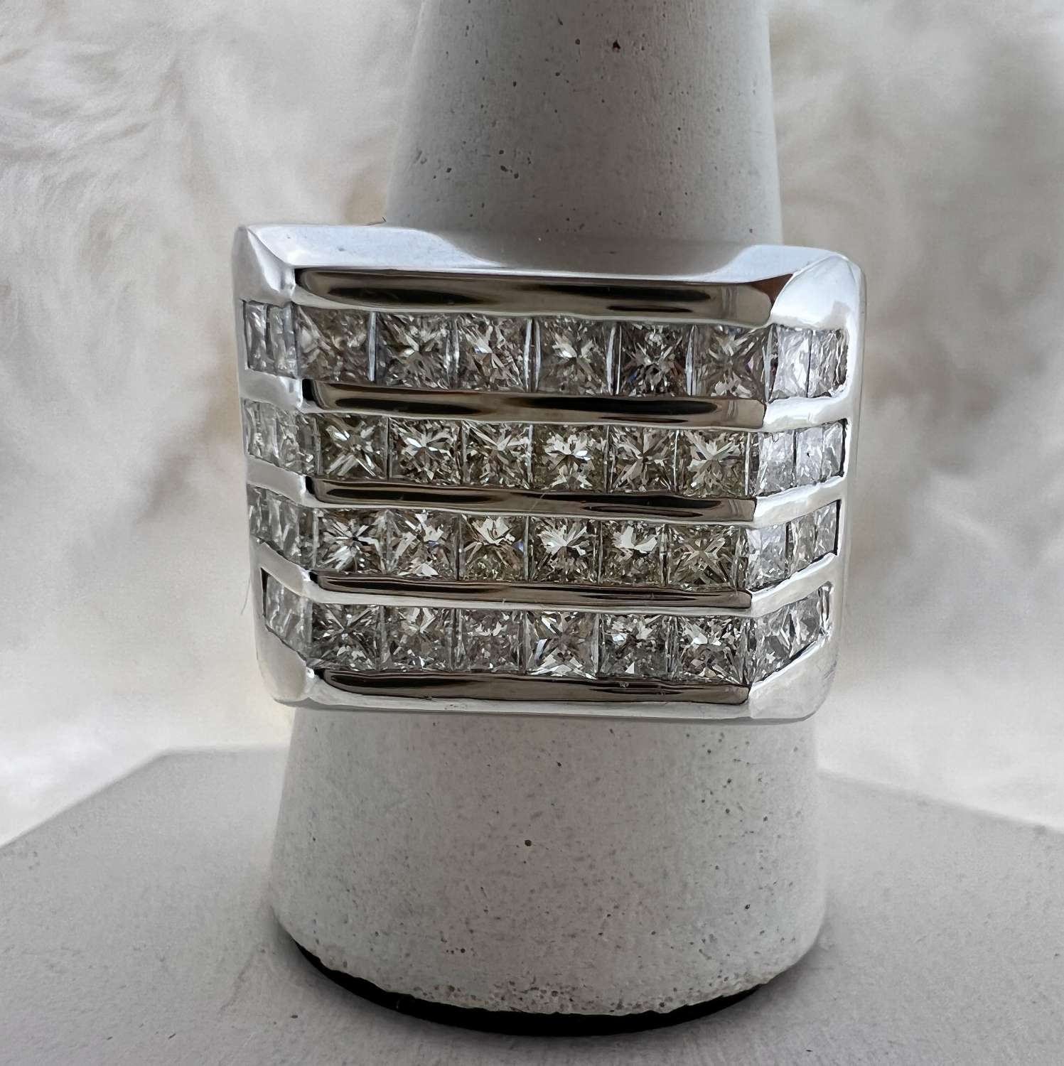 Close-up of 18kt white gold diamond band featuring 44 princess cut diamonds set in four rolls of channel setting.