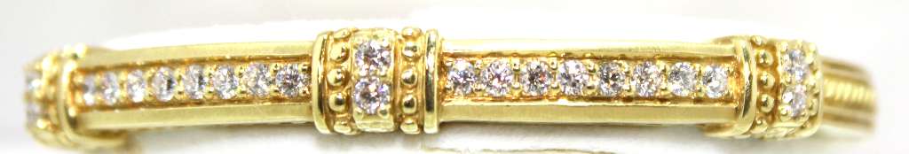 Close-up view of 18kt yellow gold diamond bangle showing round brilliant cut diamonds along band