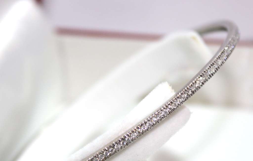 Close-up side angle of white gold diamond bangle highlighting round diamonds set in 14kt metal