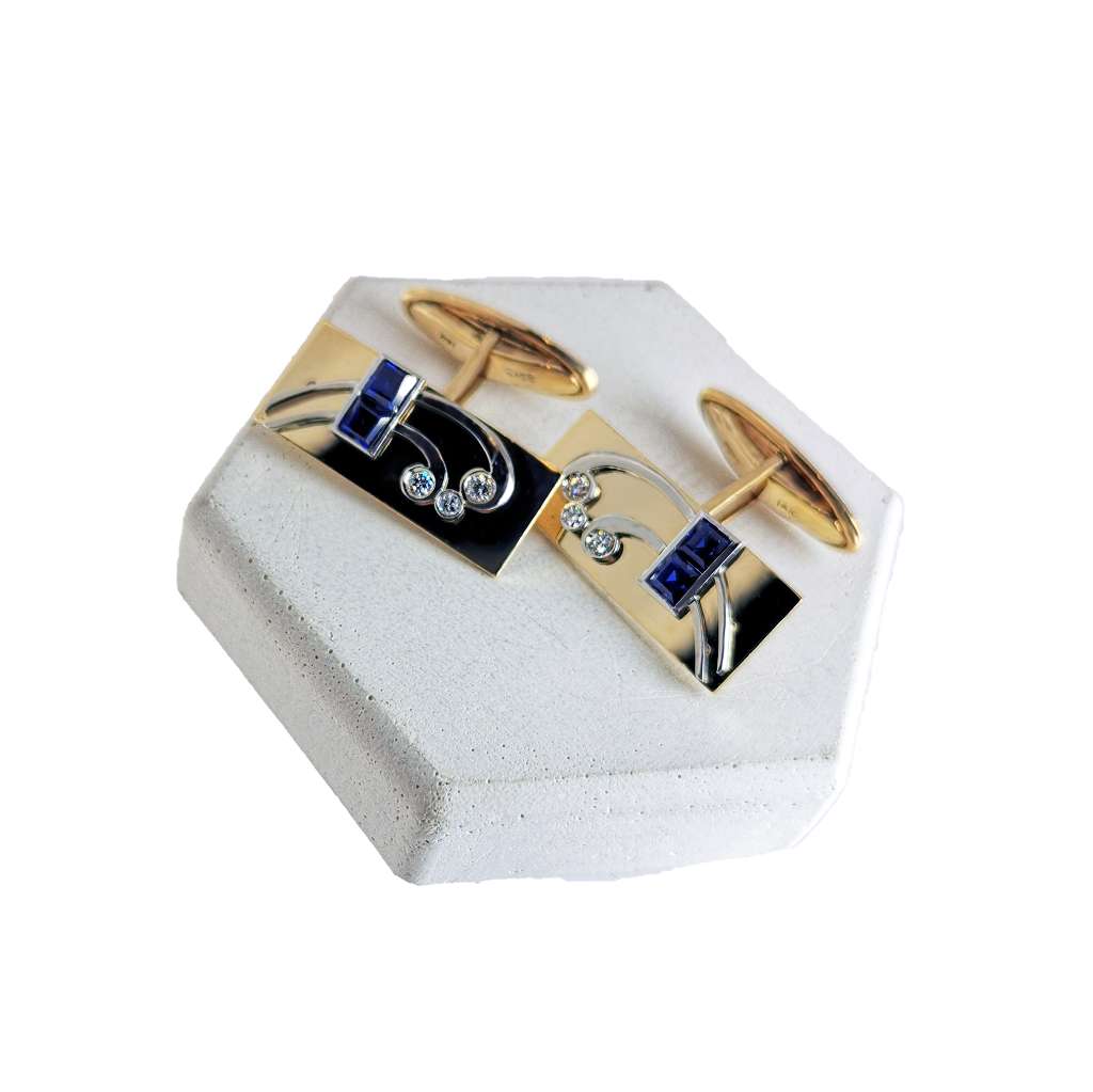 Close-up of a pair of rectangular 14kt yellow gold cufflinks featuring four square synthetic blue sapphires and six full-cut diamonds, total weight 14.56 grams