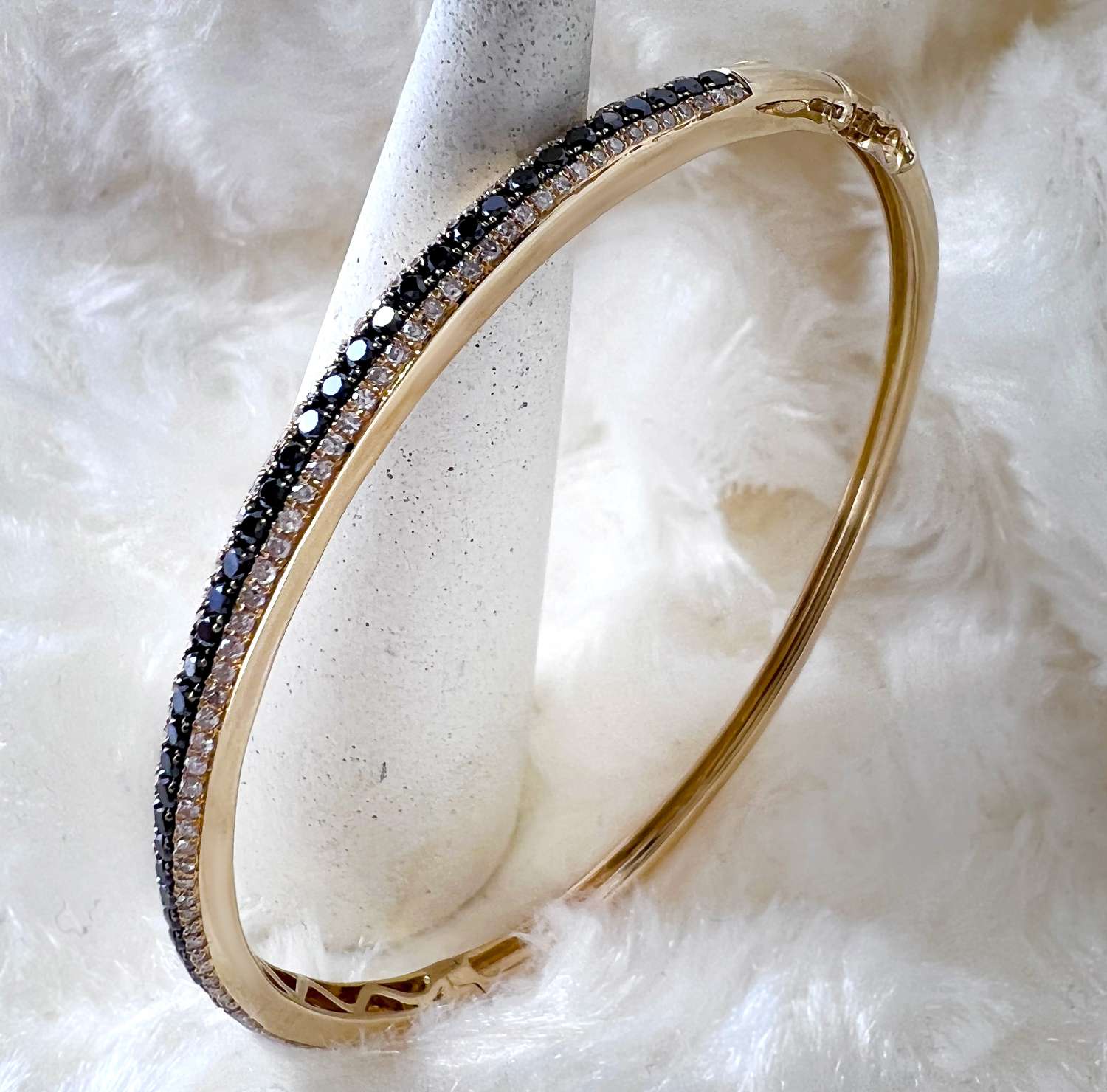Elegant 14kt yellow gold diamond bangle showcasing intricate bead-set black and colorless diamonds, angled view