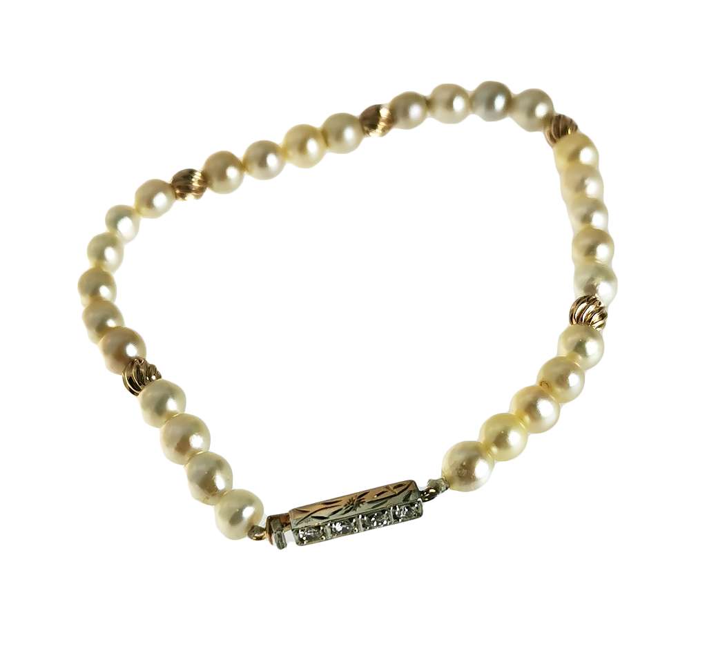 Close-up of one string of lustrous white pearls with five polished gold ball beads and a gold clasp set with four small diamonds