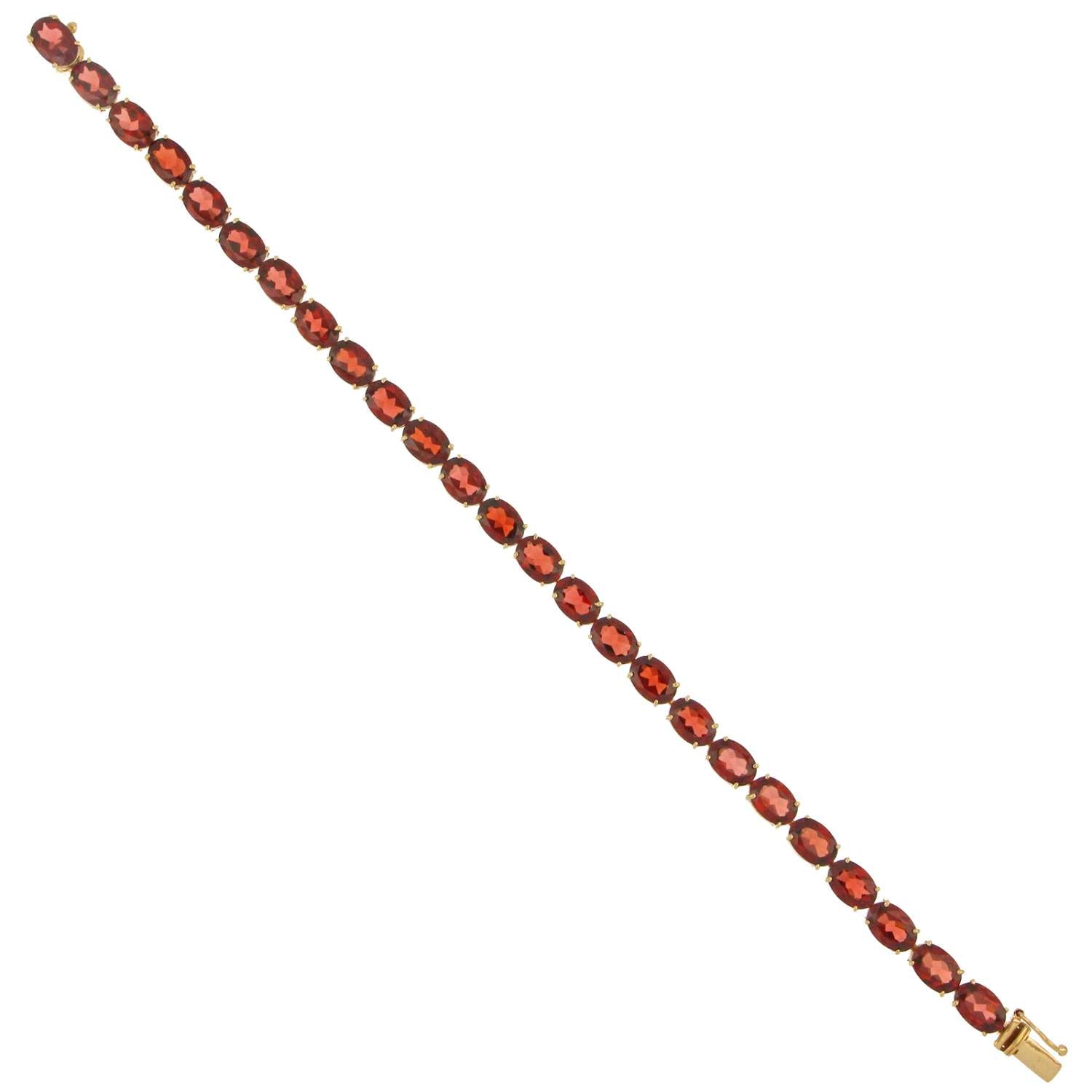 Detail shot of oval garnet stones in claw setting on 14kt yellow gold bracelet