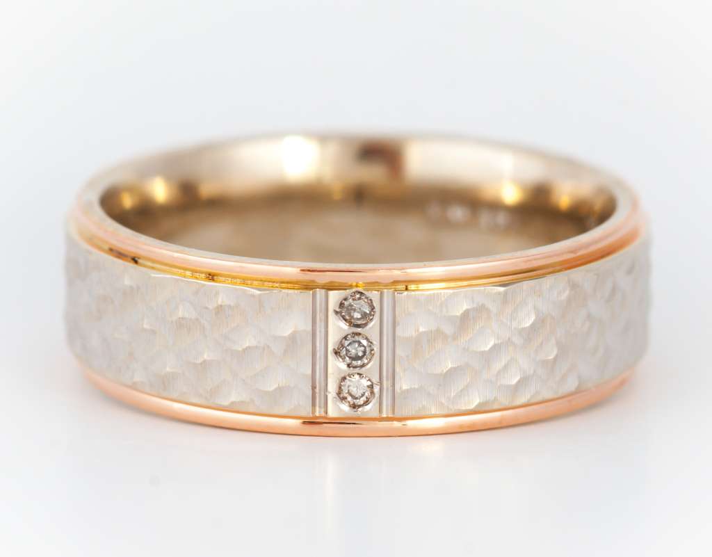 Close-up of 10kt rose and white gold diamond band showing 3 round full-cut diamonds on two-tone metal, ring size 9.5