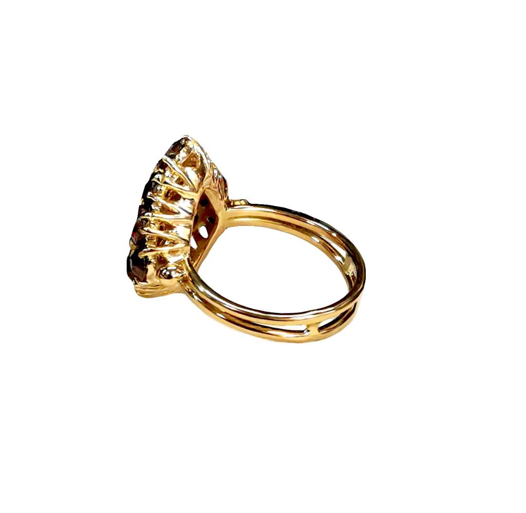 Top view of 18kt yellow gold ring featuring sixteen rich red round garnets symmetrically set around the band, total weight 7.11 grams