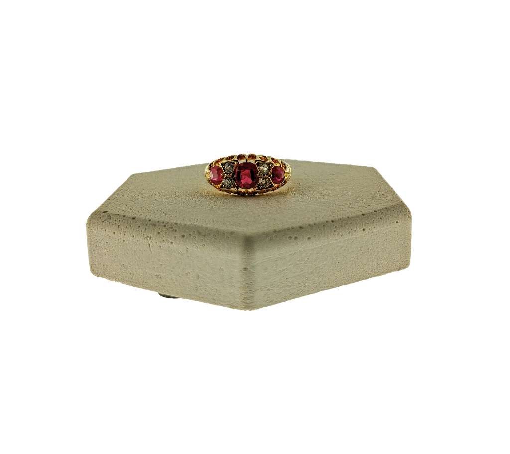 Close-up of 18kt yellow gold dinner ring showcasing three synthetic red rubies and four old mine cut diamonds