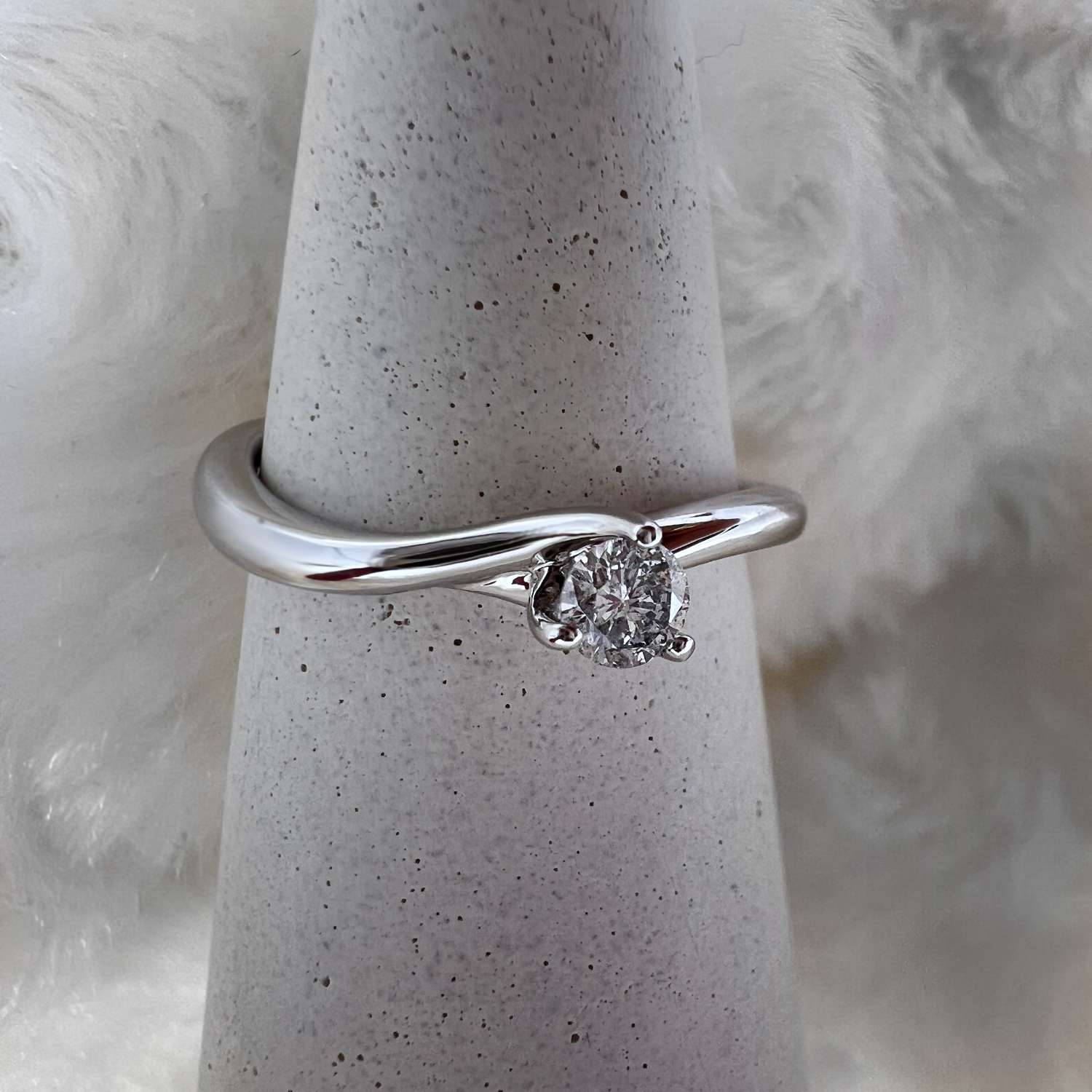 Close-up angle of 10kt white gold band with 0.15ct round diamond, highlighting claw setting and metal texture