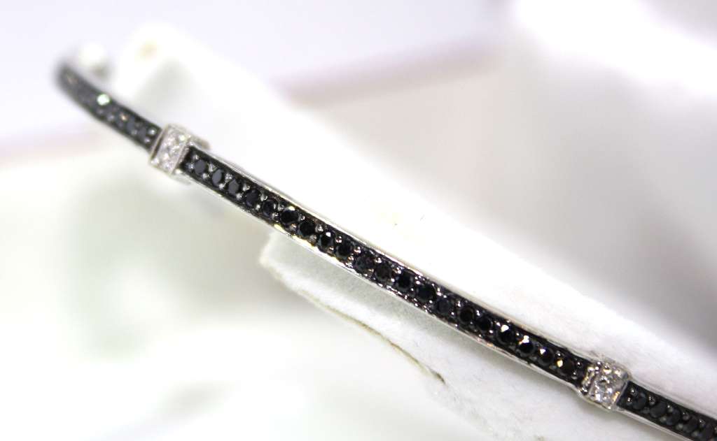 Close-up view of 18kt white gold diamond bangle detailing 24 white diamonds and 120 black diamonds