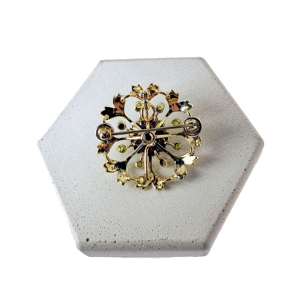 Close-up of 14kt yellow gold Victorian pearl pendant showcasing seed pearls and vibrant green peridots in round shapes
