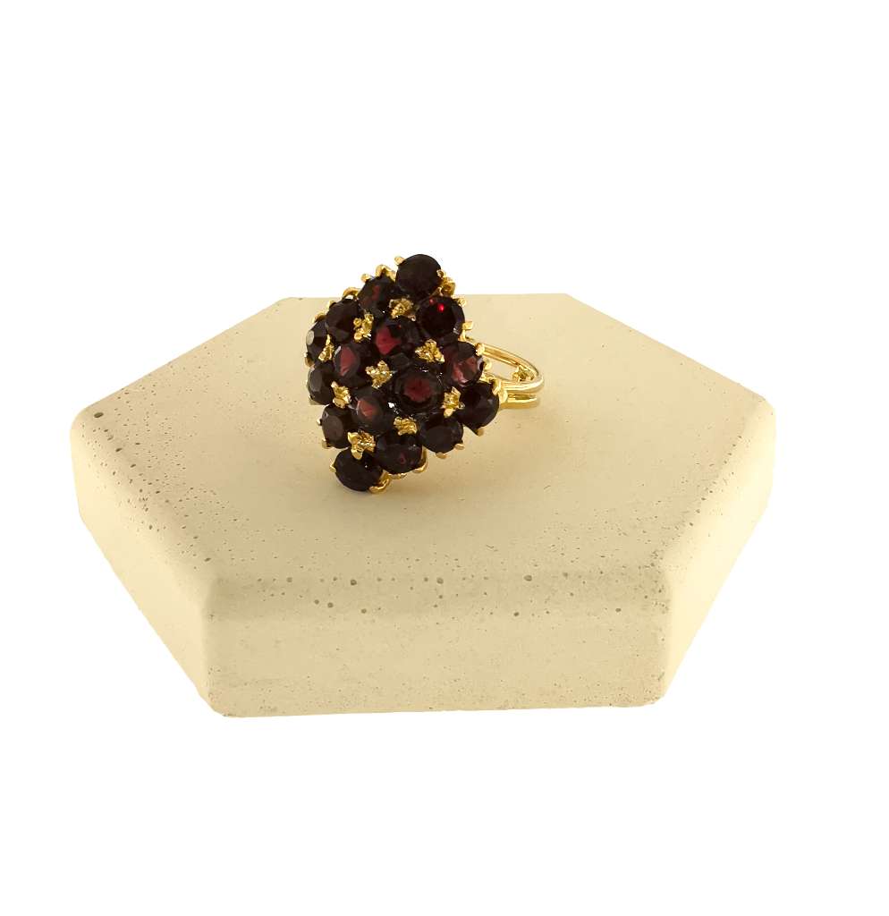 Close-up of 18kt yellow gold ring with sixteen round red garnets arranged in a continuous, elegant band, showcasing gemstone clarity and gold finish