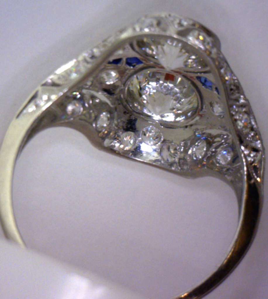 Detailed macro shot of bezel settings on a platinum ring featuring round diamonds and blue sapphires