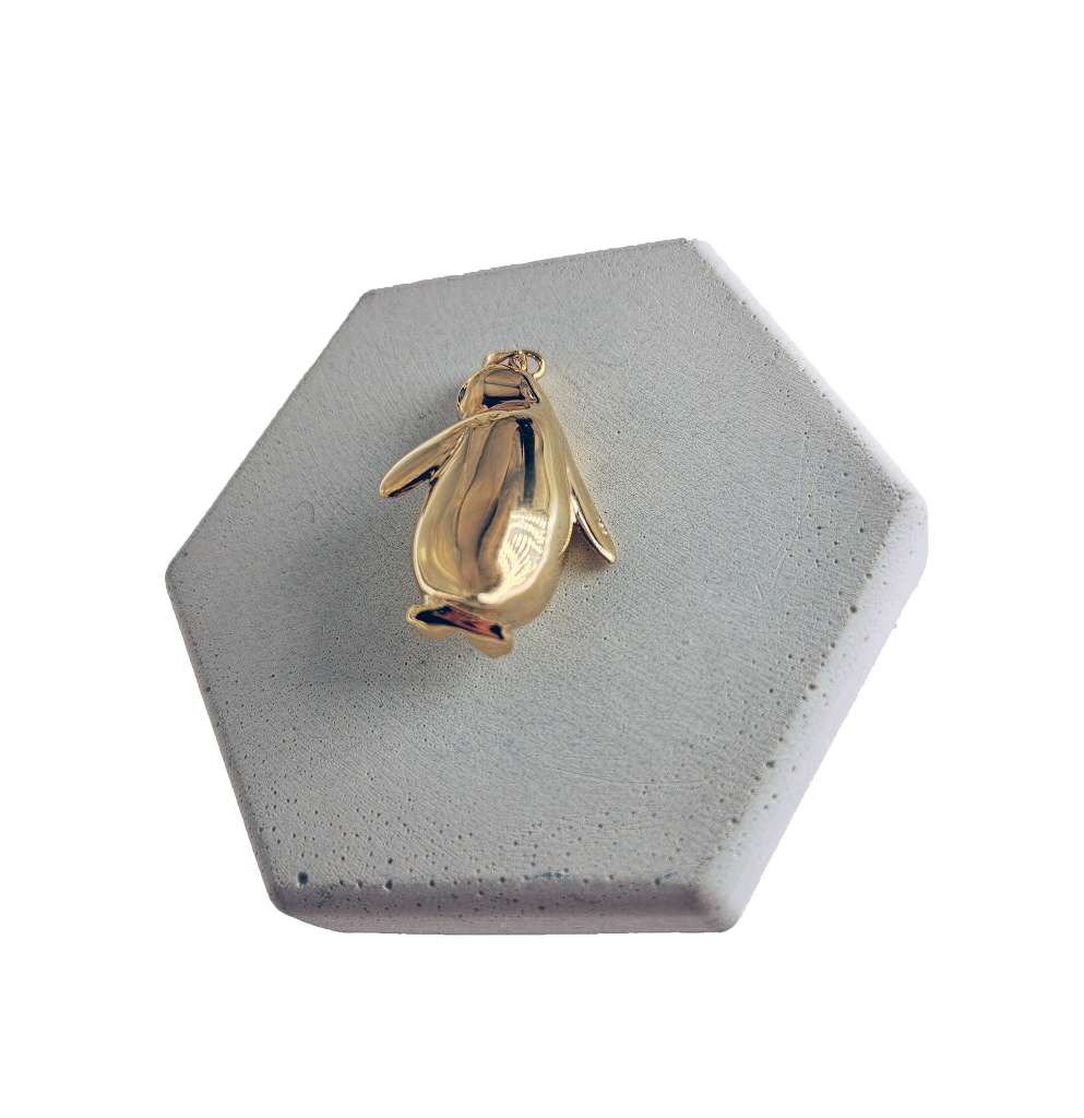 Side angle of 14kt yellow gold penguin pendant showcasing the smooth, natural elephant ivory piece and polished gold setting