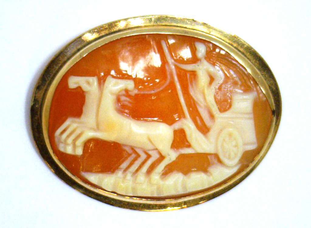 Close-up of 14kt yellow gold cameo brooch featuring an intricately carved shell cameo in warm gold setting, side angle
