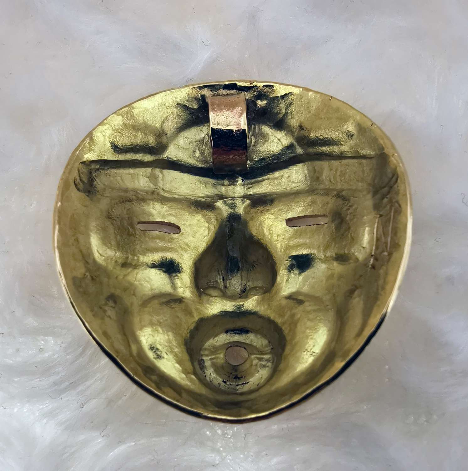 Close-up side view of 18kt yellow gold Duznakwa mask pendant by artist Corey Larocque