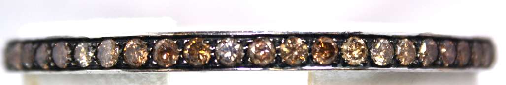 Close-up of 18kt white gold bangle adorned with round brilliant cut diamonds, showcasing the light-medium brownish yellow and near-colorless stones