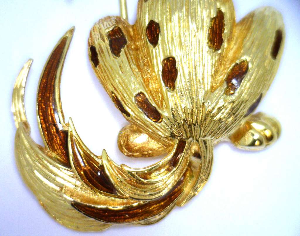 Top view of 18kt yellow gold stylized dog brooch accentuating sparkle of diamonds and deep blue sapphires