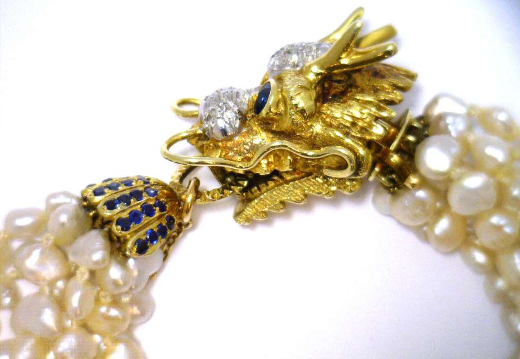 Detailed view of 14kt yellow gold clasp featuring 2 round blue sapphires and diamonds on eight strand pearl bracelet
