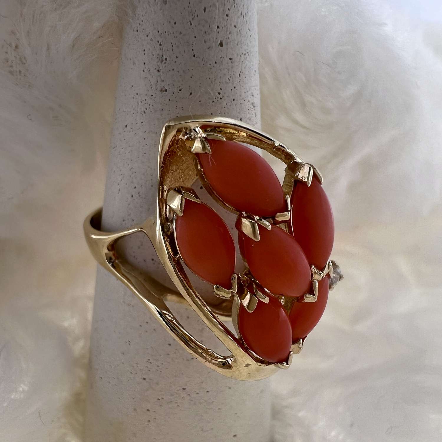 Side view of 14kt yellow gold pink coral ring showcasing diamond claw setting and polished band
