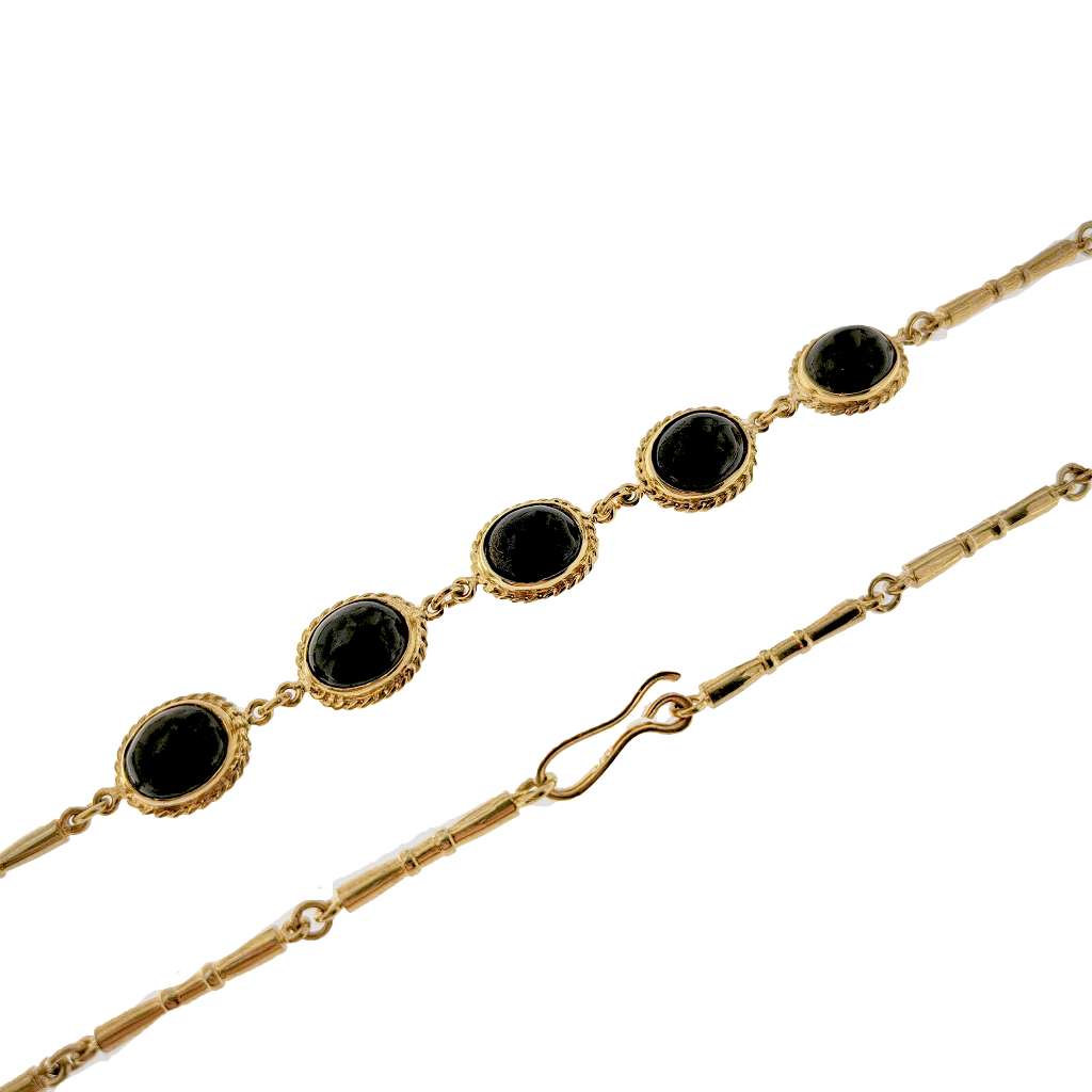 Detailed side angle of luxury 9kt yellow gold necklace showing the smooth oval black onyx stones and bezel settings