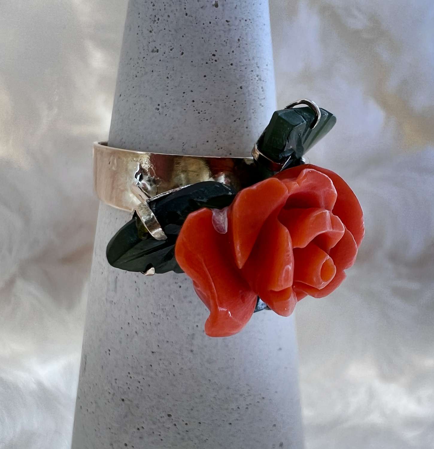 Close-up of rose flower motif carved in pink coral and jade leaves set in 9kt yellow gold ring