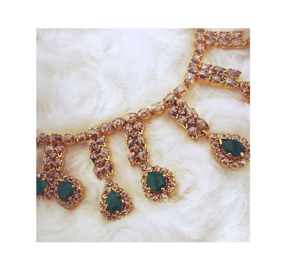 Close-up of pear shaped green emeralds and sparkling rose cut diamonds set in 22kt yellow gold