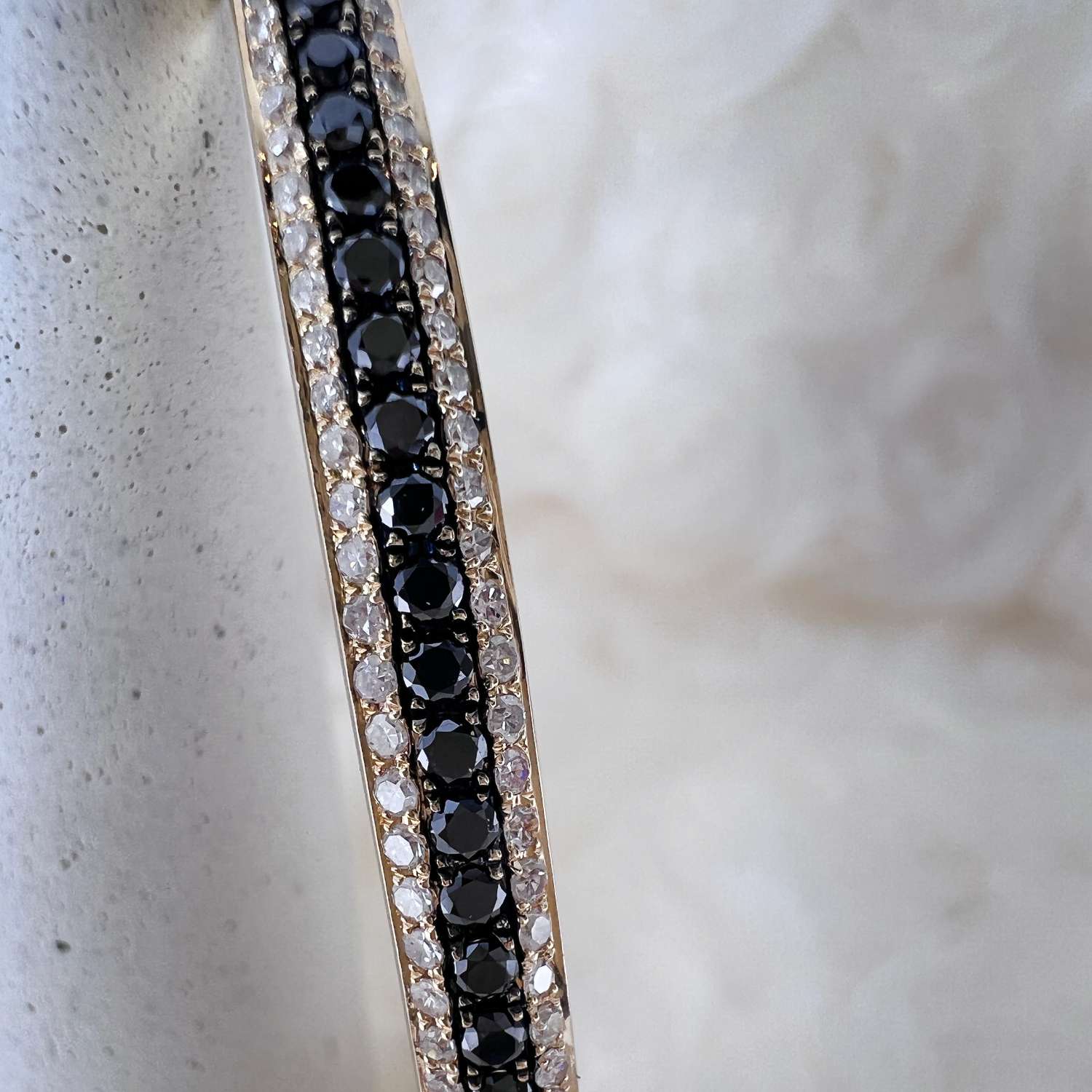 14kt yellow gold bangle set with 45 black diamonds and 132 colorless round diamonds in bead setting, close-up angle