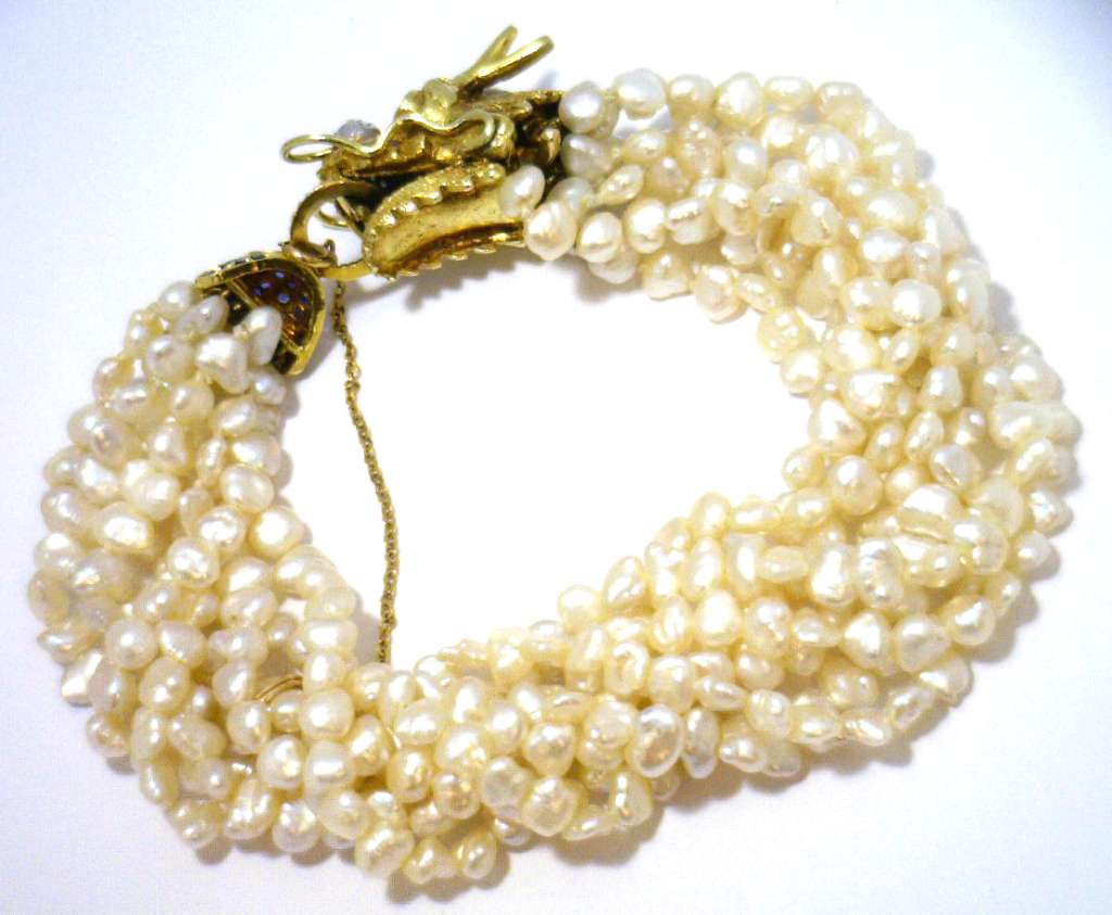 Eight strand freshwater pearl bracelet close-up of 14kt yellow gold dragon style clasp with blue sapphires and diamonds