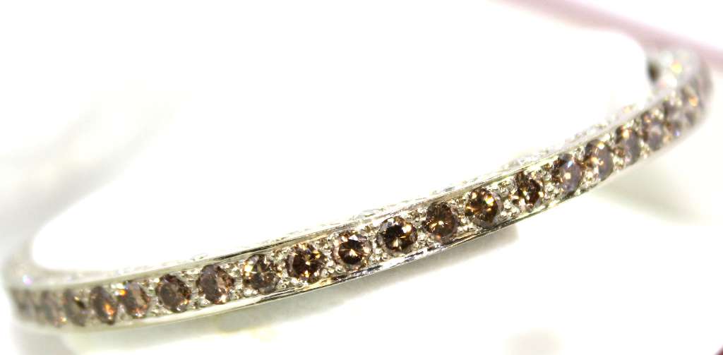 Side view of 18kt white gold diamond bangle showcasing intricate diamond setting and polished finish