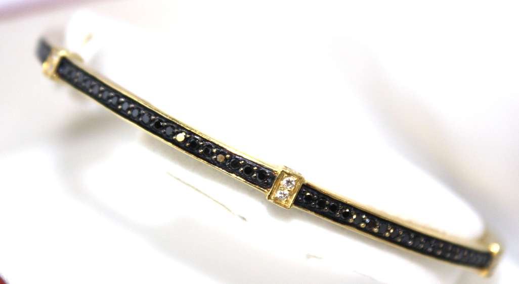 Elegant 18kt yellow gold bangle featuring contrasting black and white round brilliant cut diamonds angle view